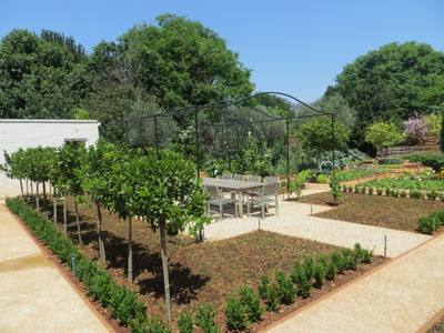 Garden design by Shirley Wallington — Seating in a veggie garden under a grapevine pergola